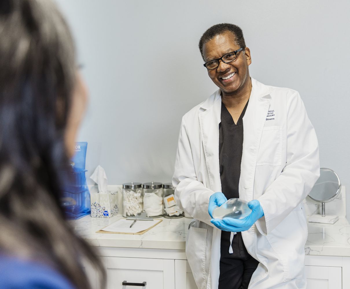 Dr. Bivens with a patient, holding a breast implant